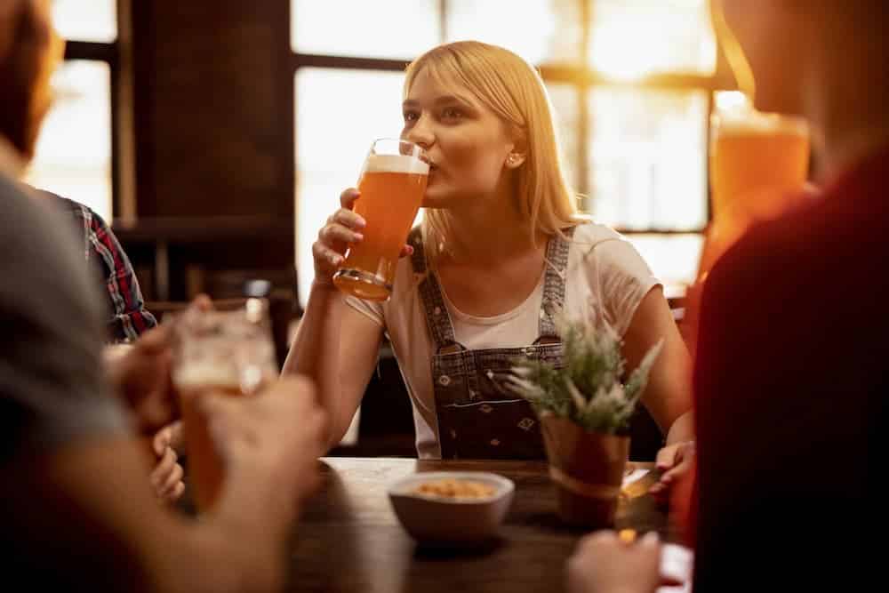 Jovem degustando cerveja lager enquanto relaxa com amigos em um bar