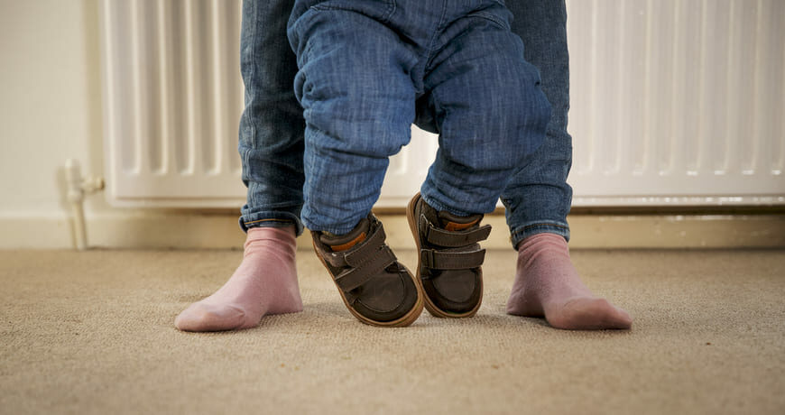 mãe ajudando filho a andar com calçado ortopédico